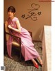 A woman in a pink dress sitting on a chair.